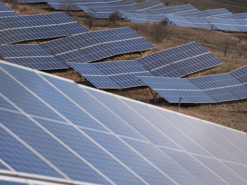 Aerial view of a large solar panel farm capturing sunlight in an open field.